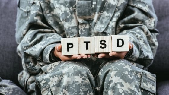 A soldier holding blocks that spell ptsd.