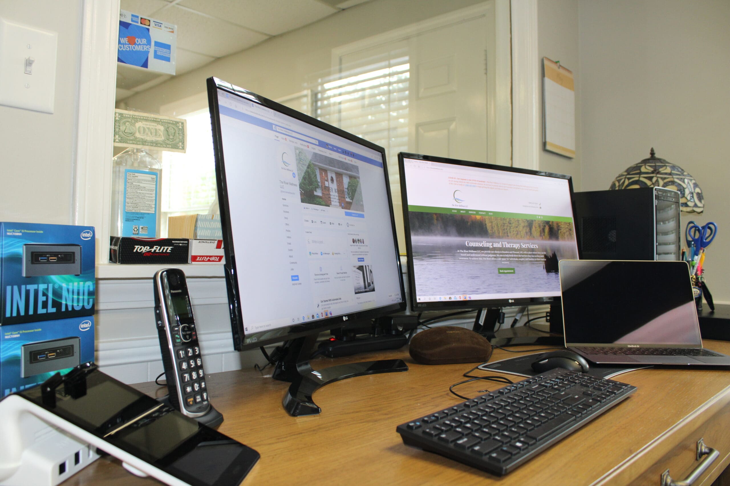 A desk with two computers and a phone on it