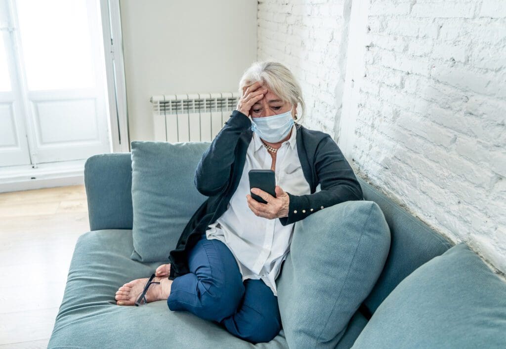 A woman sitting on the couch looking at her phone.