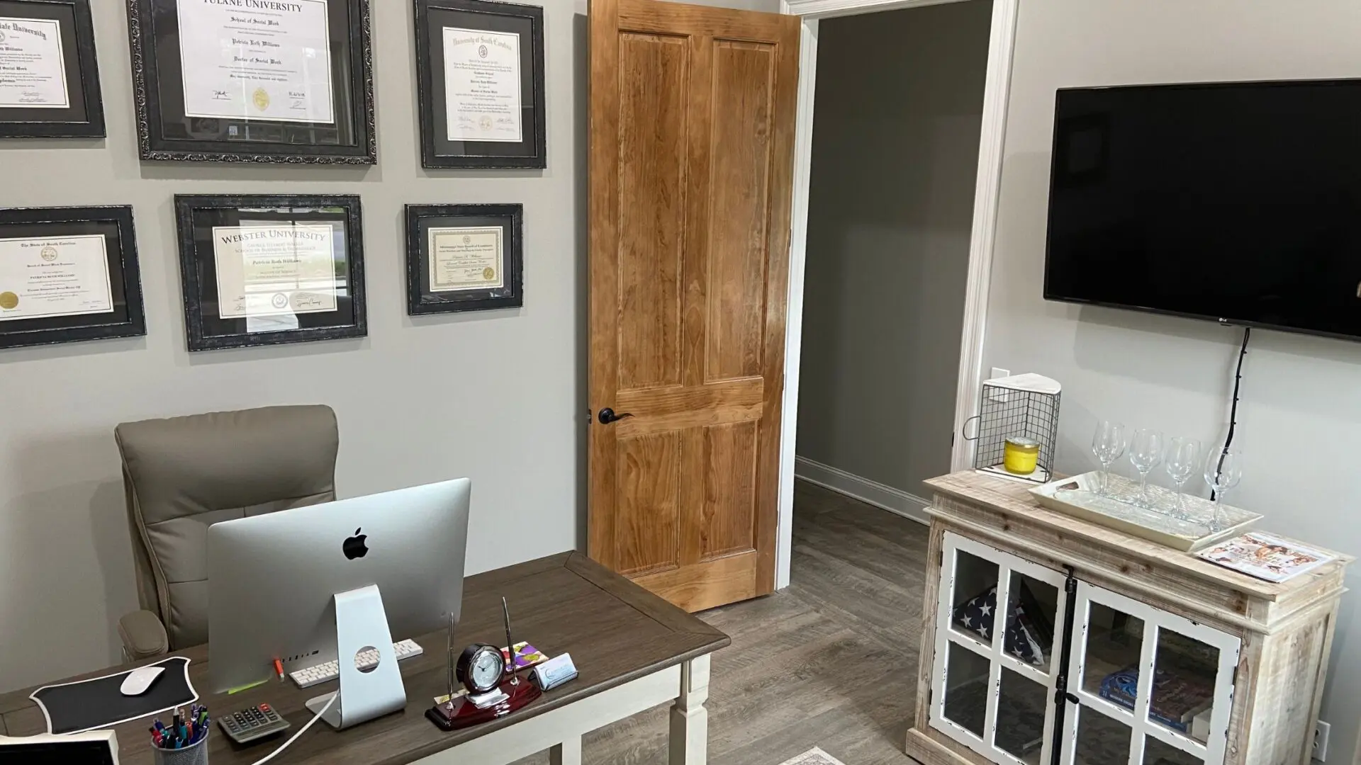 A room with a desk, computer and a door.