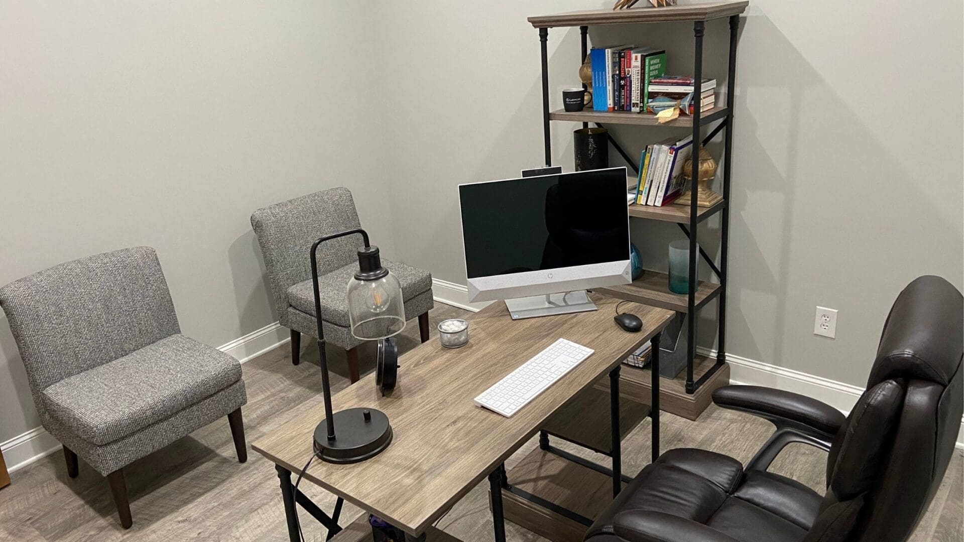 A desk with a computer and chair in front of a bookshelf.