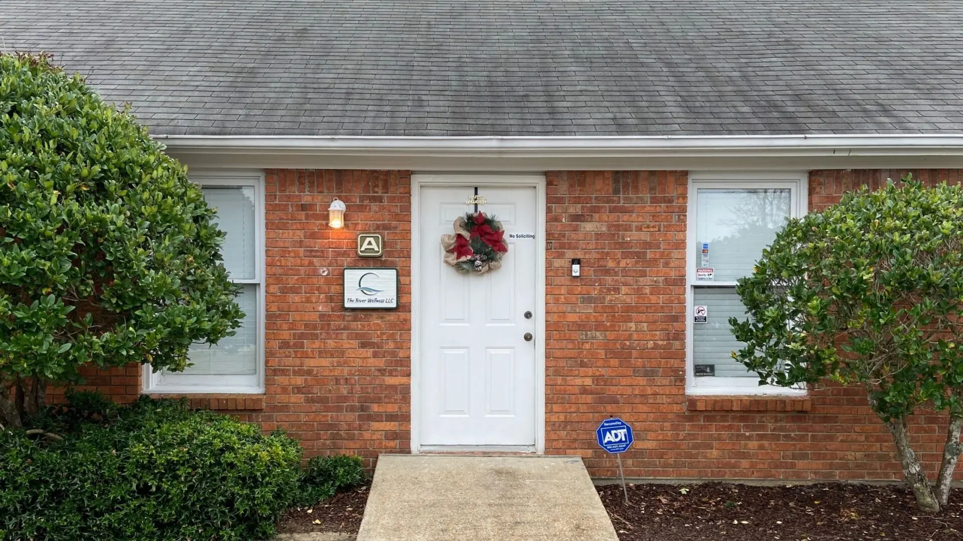 A white door and brick wall in front of a house.